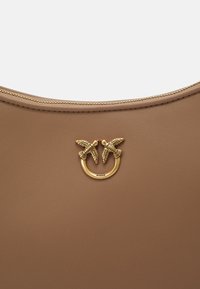 Brown leather handbag with a smooth texture, featuring a gold ring and two bird accents as hardware, and a zip closure along the top.