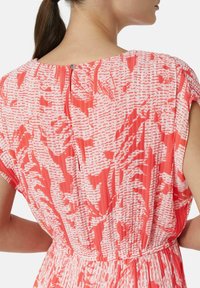 Rot-weiß gemustertes Kleid mit kurzen Ärmeln, gerafftem Bund und rückseitigem Knopfverschluss. Der Stoff hat ein strukturiertes Design.