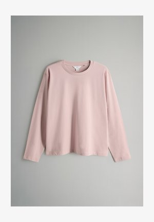 Pitkähihaiseen paita pehmeää vaaleanpunaista puuvillaa, jossa on pyöreä kaula-aukko ja rento istuvuus, sileä pintakuvio ilman näkyviä kuvioita tai tehosteita.