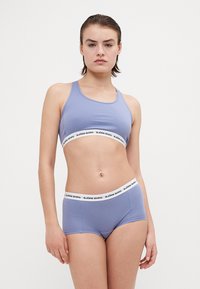 Világoskék sportmelltartó és hozzá illő fiúshort, fehér derékpánttal, amelyen a "BJÖRN BORG" felirat található. Az anyag lágy és rugalmasnak tűnik.