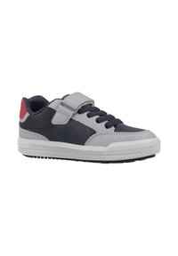 Zapatilla de caña baja con paneles azul marino y grises, cordones negros, una correa de velcro gris, acento rojo en el talón y suela blanca.