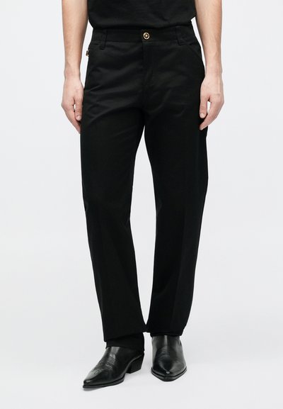 Fekete egyenes szabású nadrág arany gombbal és oldalzsebekkel. Simán szőtt anyagból készült, minimális dizájnnal.