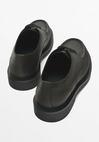 Black leather shoes with a round toe, sleek design, and a cushioned sole. Features a textured heel and subtle stitching details.