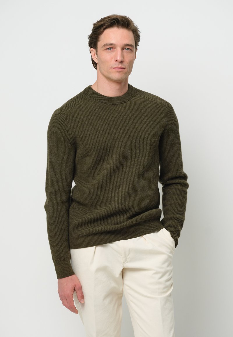 Kakhi ribbad tröja med rund hals och långa ärmar, i kombination med ljusgräddafärgade byxor med en strukturerad stickad design.