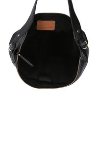 Interno di borsa in pelle nera con texture liscia, cerniera dorata e una toppa in pelle color cuoio. Presenta un design spazioso e senza fodera per un facile accesso.