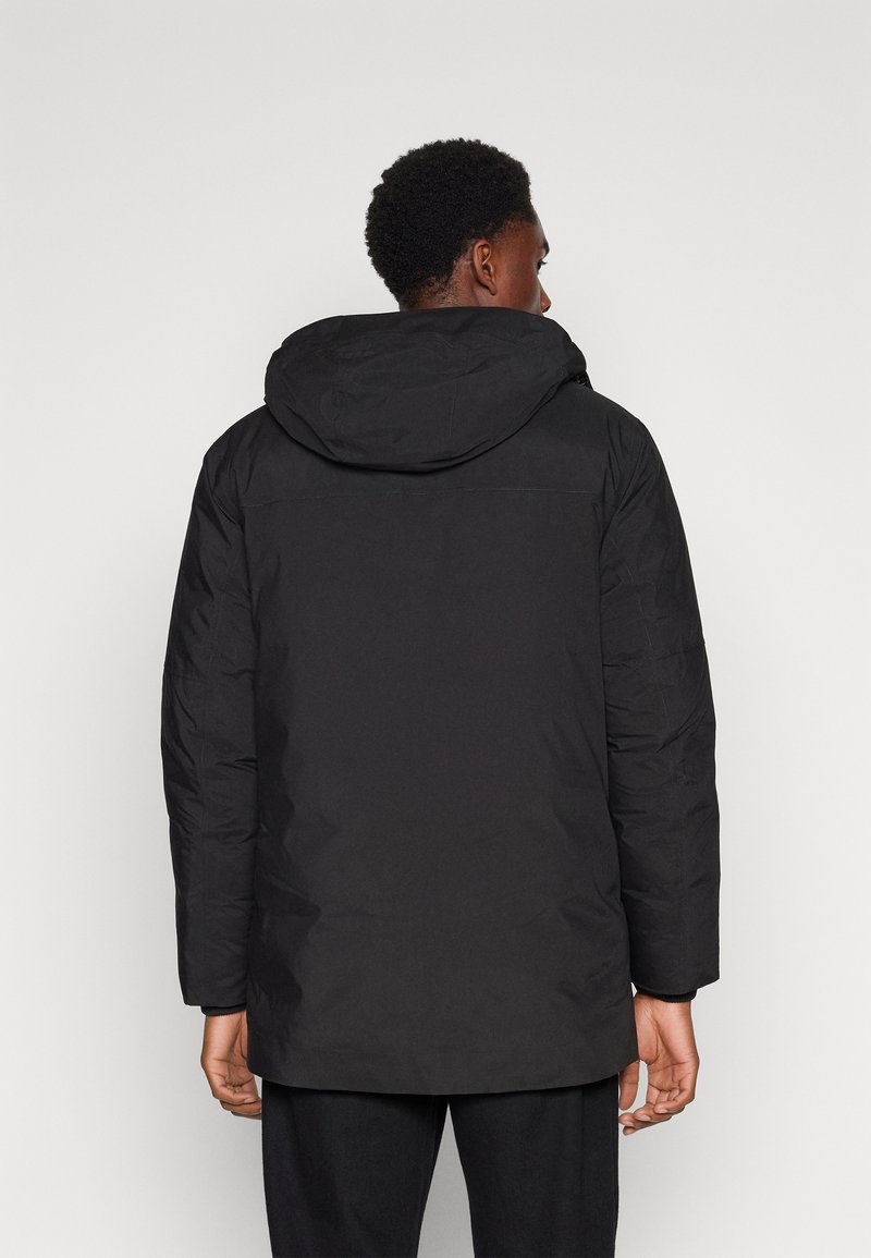 Chaqueta acolchada negra con capucha, que presenta una textura suave y mangas largas. El diseño incluye una vista trasera con detalles de costura.