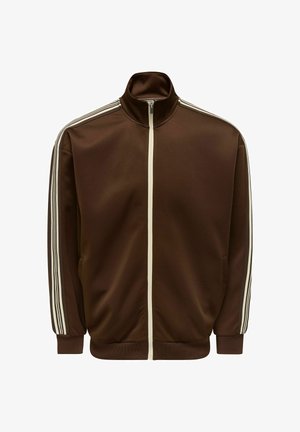 Veste de survêtement marron en tissu lisse, avec un col montant, une fermeture éclair intégrale et des bandes blanches sur les côtés des manches. Deux poches latérales.