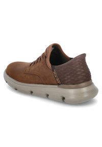 Scarpa marrone in pelle con tacco texture marrone scuro, punta rotonda e suola in gomma grigia. Presenta lacci marroni e un marchio discreto sul lato.