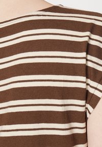 Brązowo-kremowy pasiaste ubranie z krótkimi rękawami i szerokim dekoltem. Miękka tekstura materiału i luźny krój.