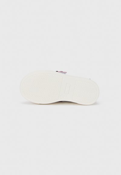 Λευκή σόλα αθλητικού παπουτσιού με υφή από καουτσούκ για πρόσφυση, που διαθέτει ένα διακριτικό ζιγκ-ζαγκ μοτίβο και μια μικρή λεπτομέρεια κοντά στη φτέρνα.