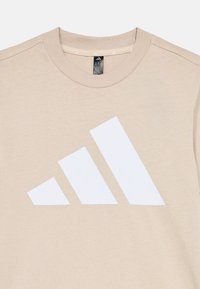 Sudadera de algodón beige con cuello redondo. Presenta un gran gráfico de logo de tres franjas blancas en el frente. Textura suave, diseño minimalista.