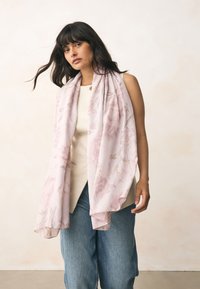 Šviesiai rožinė skara su gėlių raštu, pagaminta iš minkštos medžiagos. Lengva, laisvai krenta aplink kaklą, su subtiliais kraštais.