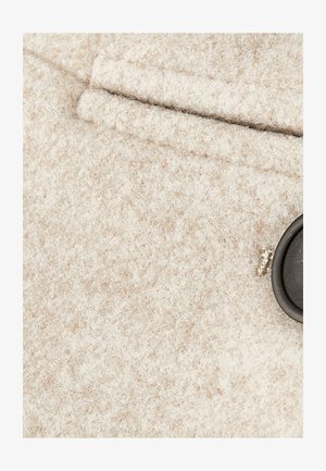 Beige woolen fabric with a soft texture, featuring a black button and a stitched pocket. Subtle flecks of color visible in the material.