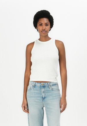 Weißes, geripptes, ärmelloses Oberteil mit rundem Halsauschnitt, ausgestattet mit einem strukturierten Strickmuster, kombiniert mit hellblauen High-Waist-Jeans.