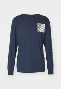 Marinblå långärmad t-shirt i bomull, med vit text "NEVER STOP EXPLORING" på bröstet och ärmen, rundad halsringning och standardpassform.