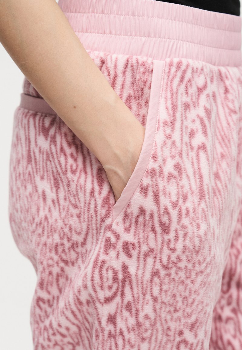 Hand resting inside the pocket of pink fuzzy pants with a subtle animal print and elastic waistband.
