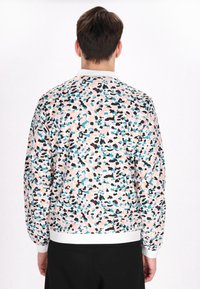 La giacca bomber colorata presenta un motivo screziato di rosa, nero e blu. I polsini e l'orlo sono bianchi, evidenziando un design sportivo.