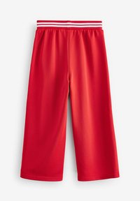 Røde atletiske shorts lavet af glat stof. Har en bred elastisk talje med to hvide striber på den øverste kant.