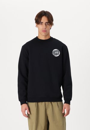 Zwarte sweatshirt met een rond, wit grafisch logo op de linkerborst. Het ontwerp heeft lange mouwen en een ronde halslijn.