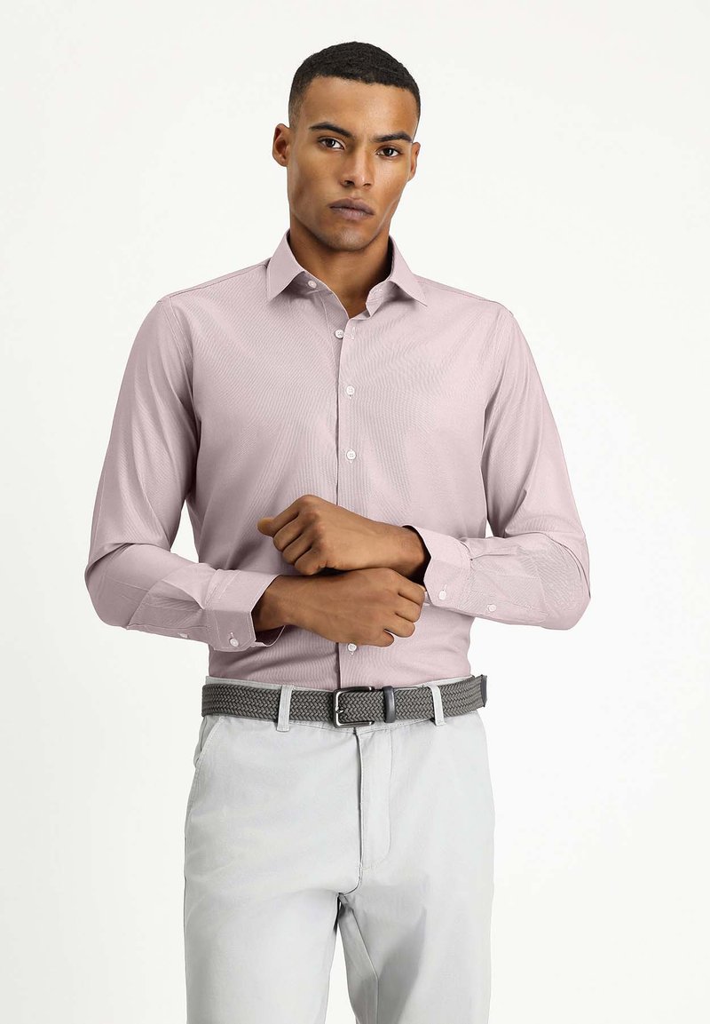 Camicia a maniche lunghe rosa chiaro con un delicato motivo testurizzato, colletto con bottoni e polsini con bottoni, abbinata a pantaloni grigio chiaro e una cintura intrecciata.