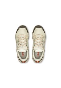 Beige waterproof shoes with gray accents, textured upper, orange laces, and a distinctive logo on the side. Round toe and cushioned sole.