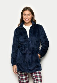 Giacca in peluche a righe blu navy, con zip completa, colletto alto e cintura regolabile in vita. Presenta maniche lunghe e due tasche laterali.