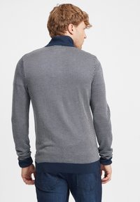 Suéter de punto en azul marino y gris claro con un patrón de espiga, que presenta un cuello alzado y puños y dobladillo acanalados.