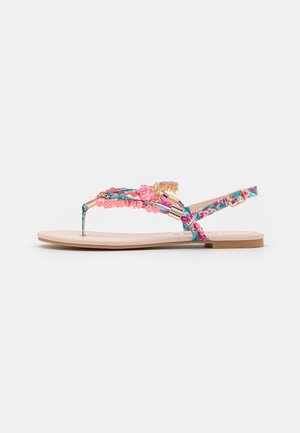 Flad sandal med blomstrede stropper dekoreret med rosa perler og gyldne accenter samt en sidelukning med spænde.