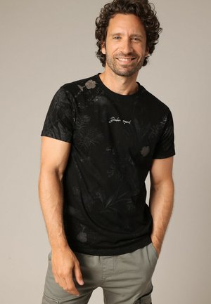 T-shirt en coton noir avec un motif floral subtil, encolure ronde, manches courtes et texte brodé à l'avant.