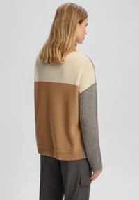 Maglione oversize con blocchi di colore beige, marrone chiaro e grigio. Realizzato in morbido materiale lavorato a maglia con orlo e polsini a costine.