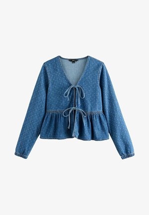 Haut en denim bleu avec un décolleté en V, des manches longues et une fermeture à nouer à l'avant. Dispose d'un design peplum et de motifs de points subtils sur l'ensemble.