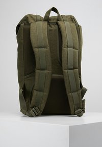 Zielono-oliwkowy plecak z wyściełanym siatkowym tyłem i regulowanymi paskami. Posiada wzmocnione szwy i zakrzywioną konstrukcję, idealny do codziennego użytku.