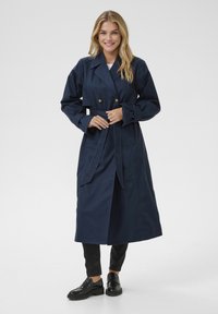Nachtblau trenchcoat met een dubbele rij knopen, een ceintuur in de taille, grote revers en knoopaccenten. Gemaakt van een gladde, duurzame stof.