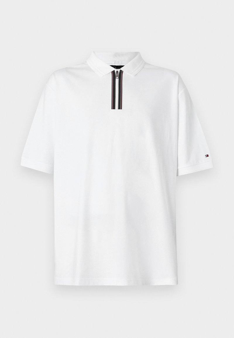 Λευκό πόλο μπλουζάκι με πλάκα σε μαύρες και κόκκινες ρίγες. Κοντά μανίκια, μαλακό βαμβακερό ύφασμα και λογότυπο στο αριστερό μανίκι.