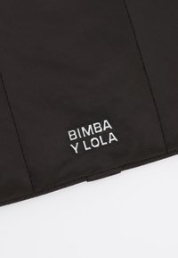 Czarna nylonowa tkanina z przeszytymi szwami i srebrnym logo "BIMBA Y LOLA". Gładka tekstura o minimalistycznym wzornictwie.