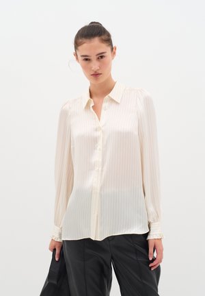 Blusa cremisi a maniche lunghe con sottili strisce verticali, chiusura con bottoni e polsini arricciati, realizzata in materiale leggero e setoso.