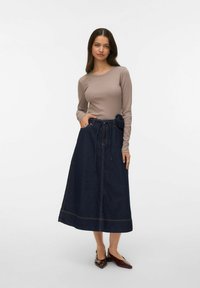 Ilgas rankovėmis smėlio spalvos viršus derinamas su tamsiai mėlyna džinsine sijono, puošto gėlių detalėmis, kišenėmis ir surišamu juosmens akcentu. Lygus tekstūra.