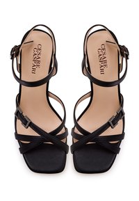 Sandales à talons hauts en cuir noir avec des orteils carrés, plusieurs sangles croisées et un accent de boucle. Doublure intérieure lisse ; design minimaliste.