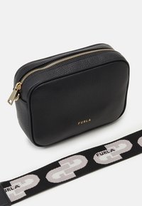 Černá kožená obdélníková taška s texturovaným povrchem, zlatým zipem a vyraženým logem "FURLA". Obsahuje vzorovaný černý popruh.