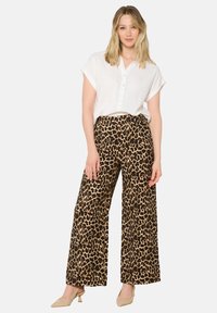 Leopardprint wijdelange broek van stof met een zachte textuur. Gepromoot met een witte blouse met korte mouwen en naakte blokhak schoenen.