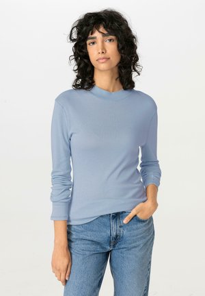 Lichtblauw longsleeve shirt met een hoge halslijn, een soepel textuur en een aansluitend ontwerp, gecombineerd met high-waisted blauwe jeans.