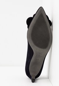 Chaussure à talon aiguille en suède noir avec un bout pointu, dotée d'une semelle en caoutchouc texturé et d'un détail en bord festonné discret. Taille 4½.