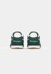 Pantofi sport din suede verde cu accente albe și talpă din cauciuc natural. Au logo brodat pe călcâi și guler căptușit pentru confort.