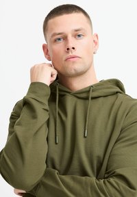 Olive green hoodie made of soft fabric, featuring a drawstring hood, long sleeves, and a relaxed fit with a smooth texture.
