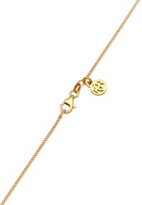 Guldfärgad kedjekaskett med en kräftkräfta och en rund berlock som har en stiliserad logotyp, med en delikat design och slät yta.