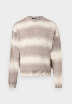 Beige og lysebrun stripete strikkegenser med lange ermer og ribbestrikkede mansjetter og nederkant, vist mot en hvit bakgrunn.