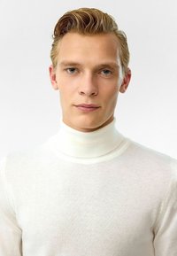 Crème-kleurige coltrui gemaakt van een fijne brei stof, met een nauwsluitende pasvorm en een gladde textuur. Geen zichtbare patronen of accenten.