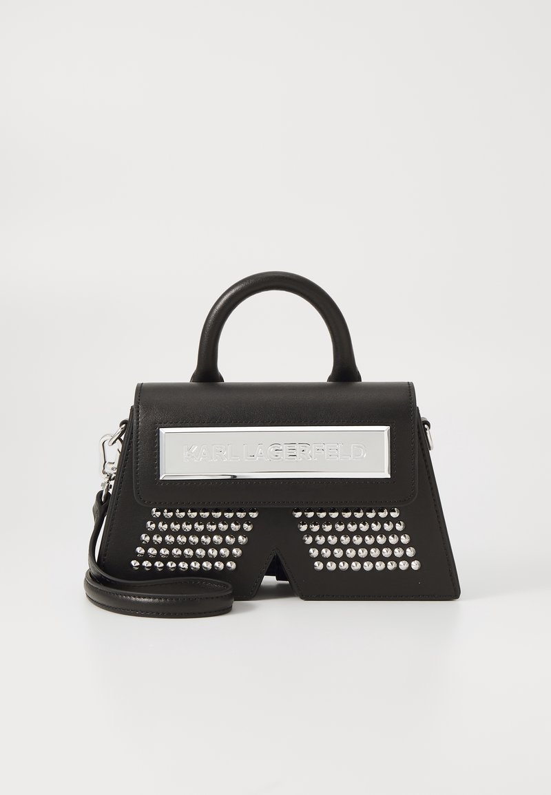 Sac à main en cuir noir avec poignée supérieure et clous argentés, avec une plaque argentée affichant le texte "Karl Lagerfeld" à l'avant.