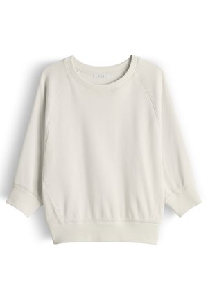 Sweatshirt à manches longues beige clair avec col rond, poignets et ourlet côtelés, présenté à plat avec l'étiquette de la marque visible à l'intérieur du col.