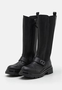 Bottes mi-mollet en cuir noir avec une semelle épaisse, dotées d'une fermeture éclair latérale, d'une bride à la cheville avec un détail boucle, et de panneaux élastiques pour un ajustement parfait.